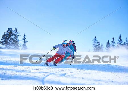 Stock Photo - Row of male and female skiers skiing down snow covered ski slope, Aspen, Colorado, USA. Fotosearch