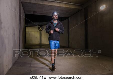Stock Photo - Runner with headlamp in tunnel. Fotosearch