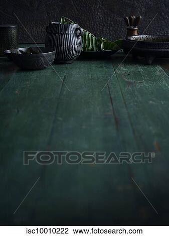Stock Image - Rustic low key still life with bowls and jug on green wooden table. Fotosearch