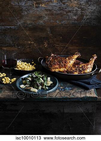 Stock Image - Rustic still life with chipotle chicken, corn and rainbow chard on wooden table. Fotosearch