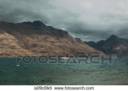 Scenic view, vessel sailing past mountains, Queenstown, Canterbury, New Zealand View Large Photo Image Stock Photography - Scenic view, vessel sailing past mountains, Queenstown, Canterbury, New Zealand. Fotosearch