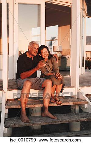 Senior couple enjoying sunset on steps in front of beach house View Large Photo Image Stock Photo - Senior couple enjoying sunset on steps in front of beach house. Fotosearch