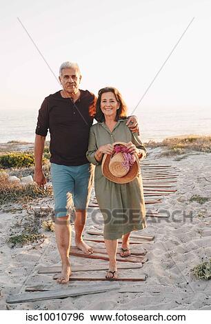 Stock Photograph - Senior couple taking walk on beach. Fotosearch