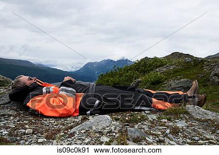 Senior male hiker taking a break lying on top of mountain, side view, Valdez, Alaska, USA View Large Photo Image Stock Image - Senior male hiker taking a break lying on top of mountain, side view, Valdez, Alaska, USA. Fotosearch