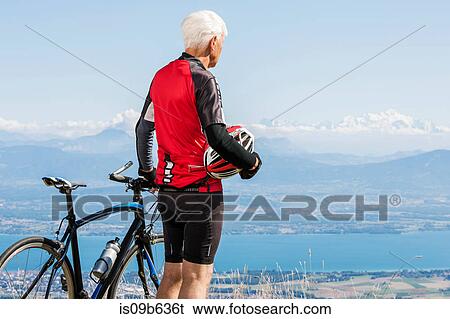 Senior man wearing cycling clothes, standing on hill, beside bicycle, looking at view, Geneva, Switzerland, Europe View Large Photo Image Stock Photograph - Senior man wearing cycling clothes, standing on hill, beside bicycle, looking at view, Geneva, Switzerland, Europe. Fotosearch