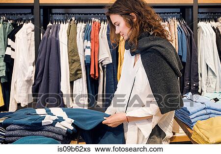 Shopper making decision in clothes shop View Large Photo Image Stock Photograph - Shopper making decision in clothes shop. Fotosearch