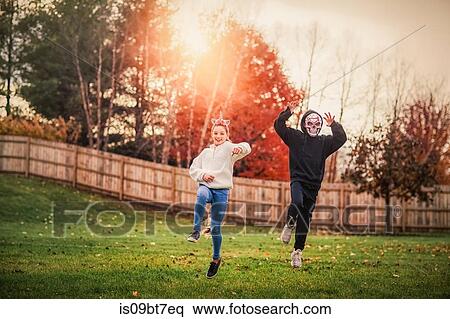 Siblings in halloween costume jumping in park View Large Photo Image Stock Photography - Siblings in halloween costume jumping in park. Fotosearch