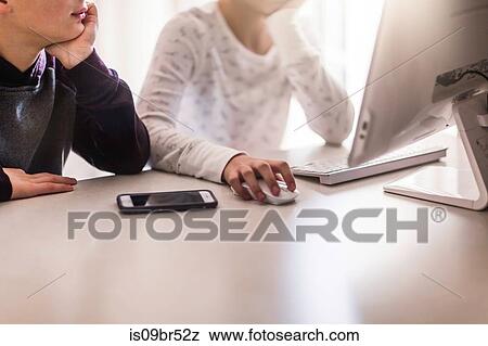 Siblings using computer at home View Large Photo Image Stock Photo - Siblings using computer at home. Fotosearch