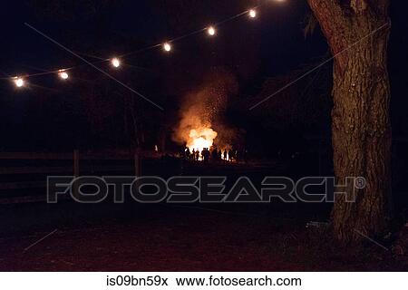 Silhouetted crowd watching bonfire in rural field at night View Large Photo Image Stock Photo - Silhouetted crowd watching bonfire in rural field at night. Fotosearch