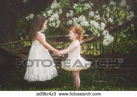 Sisters holding hands facing each other View Large Photo Image Stock Image - Sisters holding hands facing each other. Fotosearch