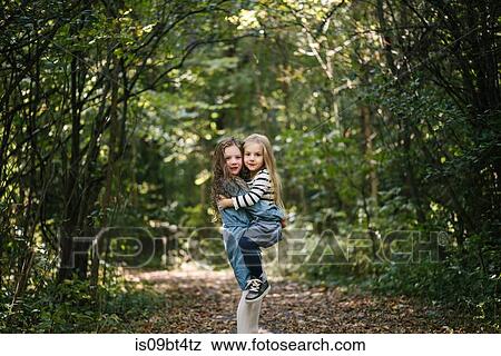 Stock Photo - Sisters hugging in forest. Fotosearch