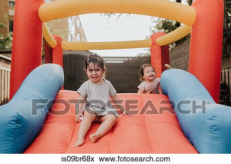 Sisters playing on inflatable slide View Large Photo Image Stock Photo - Sisters playing on inflatable slide. Fotosearch