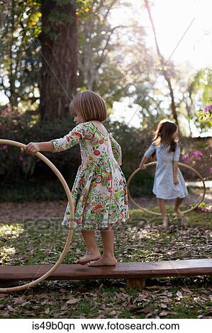 Sisters playing with plastic hoops in shaded garden View Large Photo Image Picture - Sisters playing with plastic hoops in shaded garden. Fotosearch