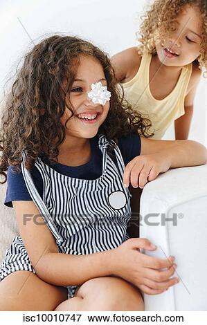 Sisters smiling over paper flower on nose View Large Photo Image Stock Photo - Sisters smiling over paper flower on nose. Fotosearch