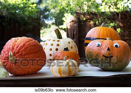 Picture - Smiley face and carved pumpkins on garden table. Fotosearch