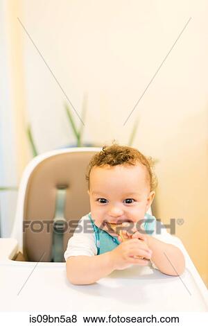 Stock Photo - Smiling baby boy sitting in highchair. Fotosearch