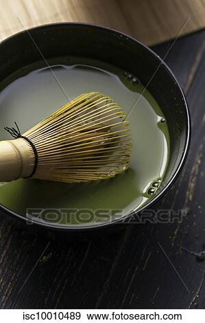 Stock Photo - Still life of matcha tea preparation with whisk in bowl of matcha tea, close up, overhead view. Fotosearch