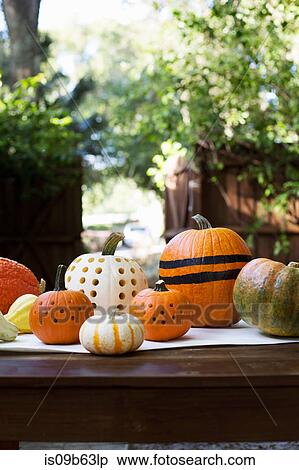 Stock Photography - Striped and carved pumpkins on garden table. Fotosearch
