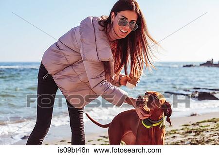 Stylish mid adult woman on beach petting her dog, portrait, Odessa, Odeska Oblast, Ukraine View Large Photo Image Picture - Stylish mid adult woman on beach petting her dog, portrait, Odessa, Odeska Oblast, Ukraine. Fotosearch