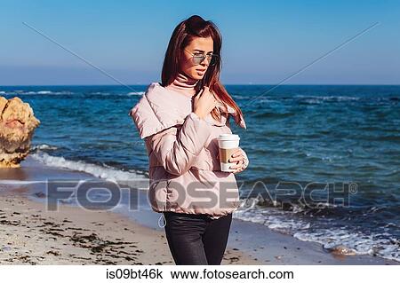 Stylish mid adult woman strolling on beach with takeaway coffee, Odessa, Odeska Oblast, Ukraine View Large Photo Image Stock Image - Stylish mid adult woman strolling on beach with takeaway coffee, Odessa, Odeska Oblast, Ukraine. Fotosearch