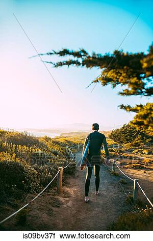 Stock Image - Surfer with surfboard on beach, Morro Bay, California, United States. Fotosearch