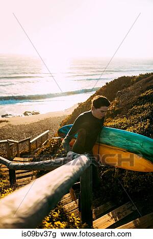 Stock Image - Surfer with surfboard on beach, Morro Bay, California, United States. Fotosearch