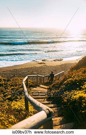 Stock Image - Surfer with surfboard on beach, Morro Bay, California, United States. Fotosearch