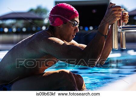 Stock Image - Swimmer hanging onto pool ladder. Fotosearch