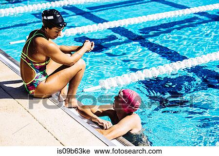 Swimmer sitting at end of pool talking to friend View Large Photo Image Stock Image - Swimmer sitting at end of pool talking to friend. Fotosearch