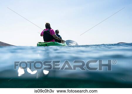 Stock Photo - Teenage boy and mother sea kayaking, surface level rear view, Limnos, Khios, Greece. Fotosearch