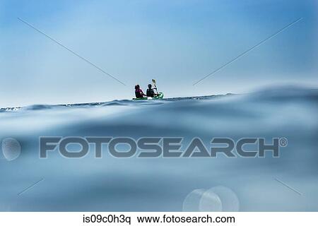 Stock Photography - Teenage boy and mother sea kayaking, surface level distant view, Limnos, Khios, Greece. Fotosearch