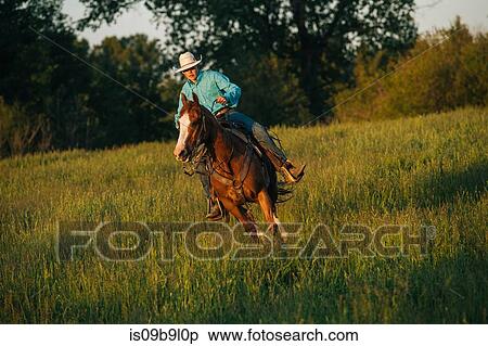 Stock Photography - Teenage boy riding horse in field. Fotosearch
