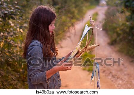 Stock Image - Teenage girl gazing at kite on dirt track. Fotosearch