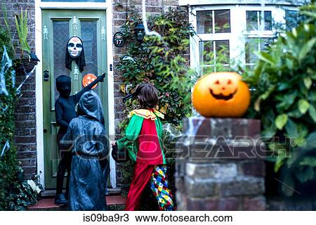 Three boy in halloween costumes, standing at door, trick or treating, rear view View Large Photo Image Stock Image - Three boy in halloween costumes, standing at door, trick or treating, rear view. Fotosearch