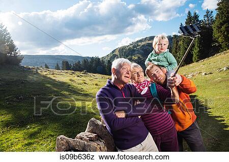 Three generation family in rural setting, taking selfie, using smartphone and selfie stick, Geneva, Switzerland, Europe View Large Photo Image Stock Photo - Three generation family in rural setting, taking selfie, using smartphone and selfie stick, Geneva, Switzerland, Europe. Fotosearch