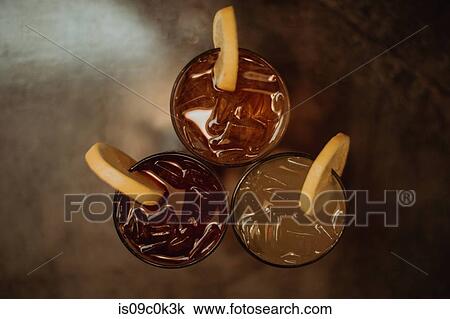 Stock Image - Three glasses of iced fruit drinks on cafe table, overhead view. Fotosearch
