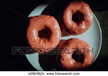 Stock Photo - Three iced doughnut holes on cafe table, low key overhead view. Fotosearch