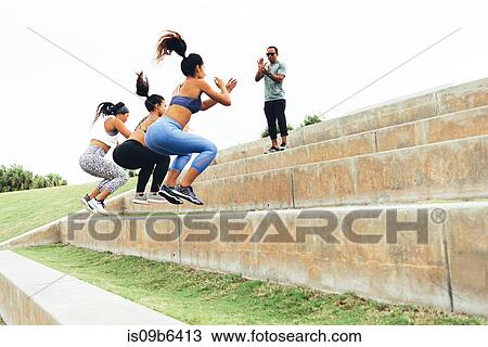 Stock Image - Three women working out with personal trainer, South Point Park, Miami Beach, Florida, USA. Fotosearch