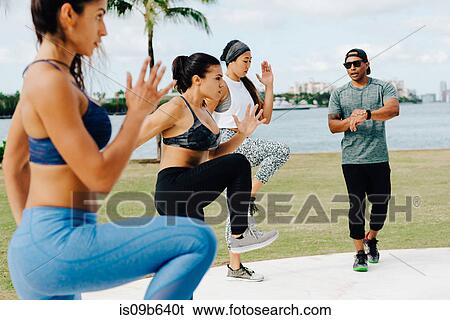 Stock Photograph - Three women working out with personal trainer, South Point Park, Miami Beach, Florida, USA. Fotosearch