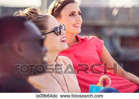 Picture - Three young adult friends at roof party in London, UK. Fotosearch