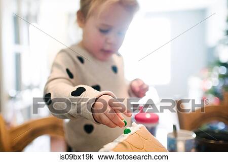 Toddler girl decorating gingerbread house for Christmas View Large Photo Image Stock Image - Toddler girl decorating gingerbread house for Christmas. Fotosearch
