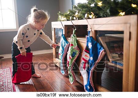 Toddler girl hanging up Christmas stockings View Large Photo Image Stock Image - Toddler girl hanging up Christmas stockings. Fotosearch