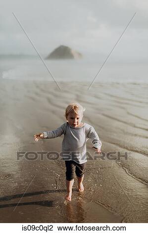 Stock Image - Toddler running on beach, Morro Bay, California, United States. Fotosearch