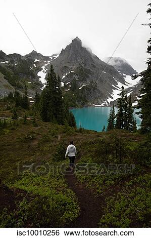 Stock Photograph - Tourist exploring wilderness, Alpine Blue Lake, Washington, USA. Fotosearch