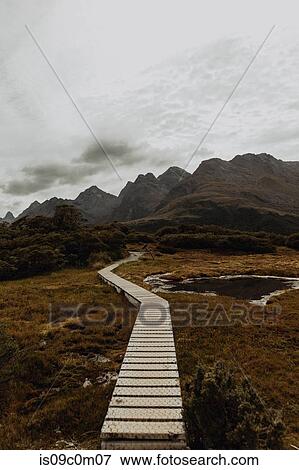 Stock Photo - Trail path leading towards mountain ranges, Queenstown, Canterbury, New Zealand. Fotosearch