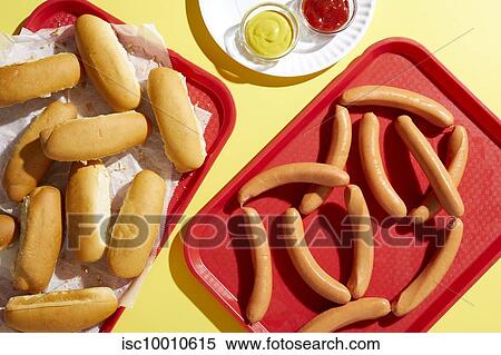 Stock Photography - Tray of bread finger rolls and tray of hotdogs on yellow background. Fotosearch