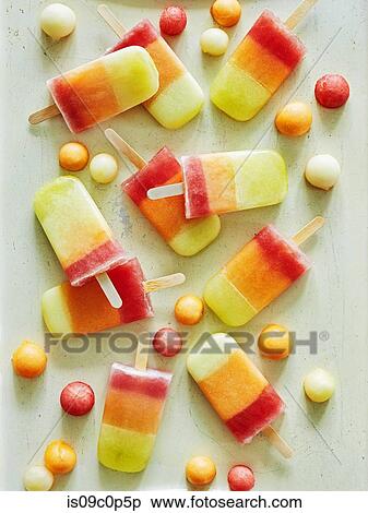 Stock Photography - Tri-coloured ice lollies and ice balls on table. Fotosearch