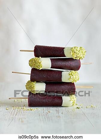 Tri-coloured ice lollies stacked on table, white background View Large Photo Image Stock Photograph - Tri-coloured ice lollies stacked on table, white background. Fotosearch
