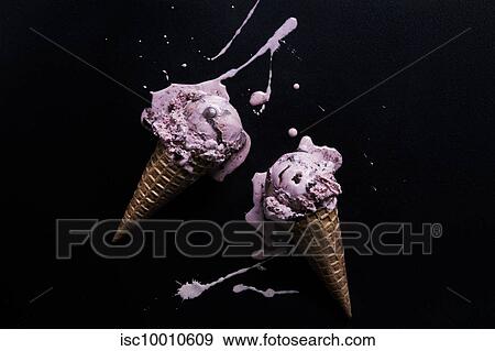 Stock Photo - Two chocolate chip raspberry ice-cream cones with melted splash against black background, overhead view. Fotosearch