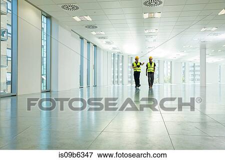Two construction workers walking through empty office space View Large Photo Image Stock Photo - Two construction workers walking through empty office space. Fotosearch